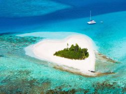 idyllic heart-shaped island in the Caribbean with a luxury yacht anchored close by - perfect honeymoon destination