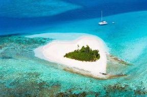 idyllic heart-shaped island in the Caribbean with a luxury yacht anchored close by - perfect honeymoon destination