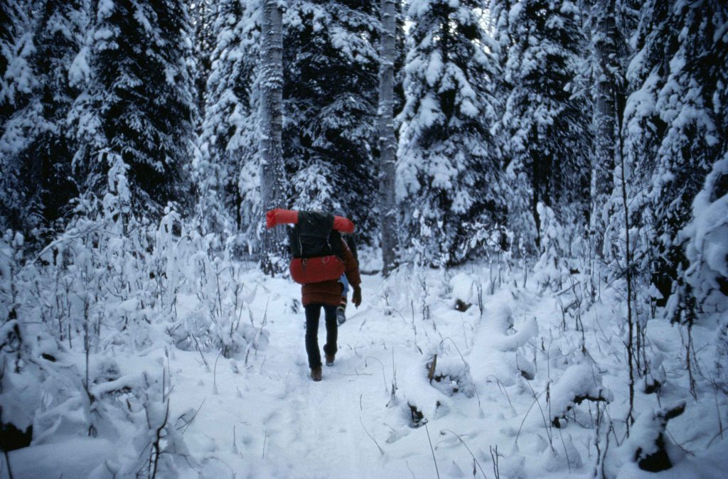 Man_with_backpacking_walking_in_forest_at_winter
