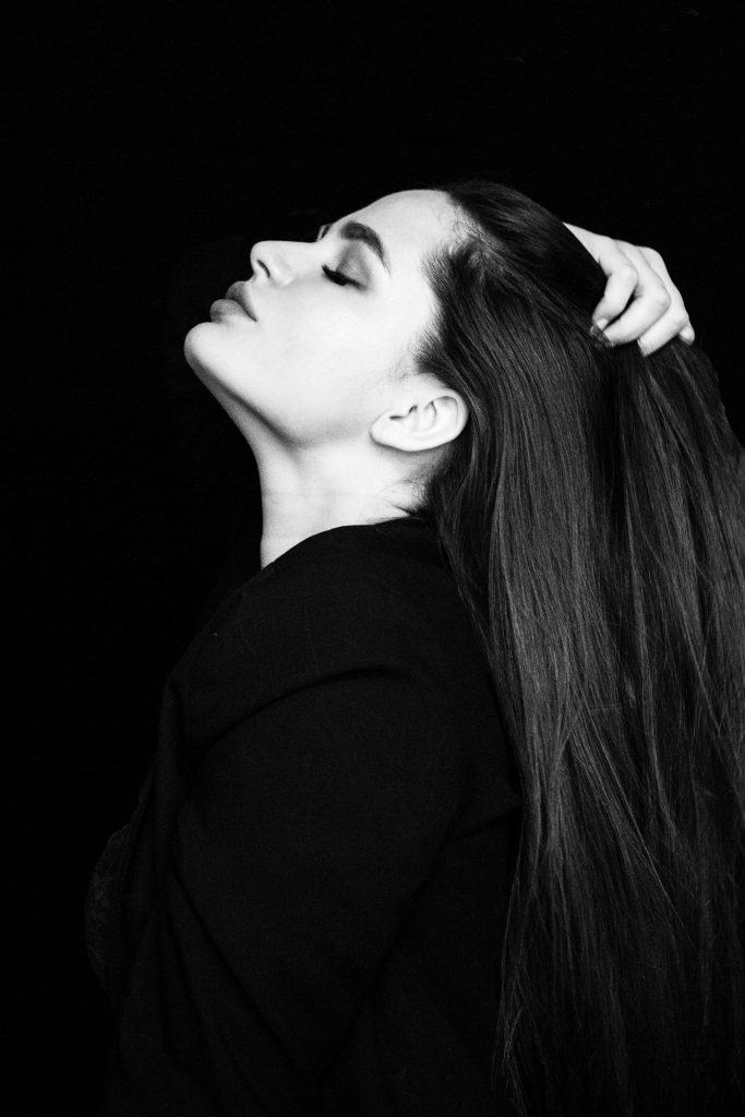 grayscale-photo-of-woman-with-her-eyes-closed-touching-her-2166774