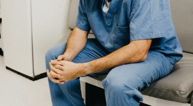 man-wearing-blue-scrub-suit-and-mask-sitting-on-bench-3279197