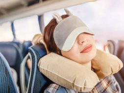 Womang in sleep mask and with pillow travelling in bus
