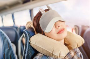 Womang in sleep mask and with pillow travelling in bus