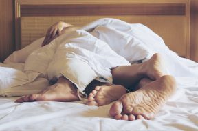 Couple on white bed in hotel room focus at feet