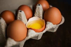 fresh-brown-eggs-broken-egg-with-yolk-eco-tray-made-from-recycled-paper-dark-wooden