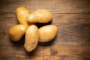 Raw potato on wooden background.