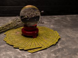 Forecasting, fortune telling, occult concept. Cartomancy, occult science. Crystal ball and tarot cards on grey background. Magic tarot cards spread on a table surrounding crystal ball for magic ritual