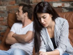Sad pensive young girl thinking of relationships problems sitting on sofa with offended boyfriend, conflicts in marriage, upset couple after fight dispute, making decision of breaking up get divorced