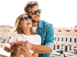 Portrait of smiling beautiful girl and her handsome boyfriend. Woman in casual summer jeans clothes. Happy cheerful family. Female having fun on the street background in sunglasses