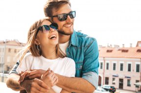 Portrait of smiling beautiful girl and her handsome boyfriend. Woman in casual summer jeans clothes. Happy cheerful family. Female having fun on the street background in sunglasses