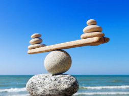 Symbolic scales of stones on the background of the sea and blue sky. Concept of harmony and balance. Pros and cons concept