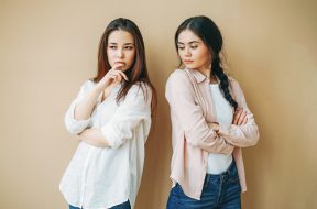 Young upset girls friends in casual offended at each other isolated on the beige background jealousy