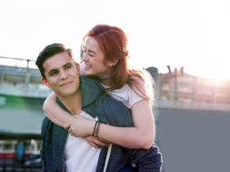Love story. Pretty young woman smiling while hugging her boyfriend