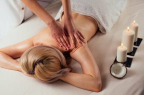 Ayurvedic relaxing.health beauty happy blonde woman in spa salon getting massage .Beautiful girl enjoying day spa resort, lying down on the table treatment procedure next to the candle fire