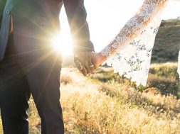 An Interracial couple holding hands backlit by the flaring sun