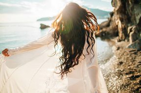 girl running dreamy with wind in hair and sunflare on beach sunset. defocus