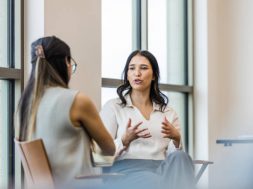 The young adult woman gestures as she details her experience during the interview with the unrecognizable businesswoman.