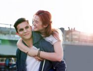 Love story. Pretty young woman smiling while hugging her boyfriend